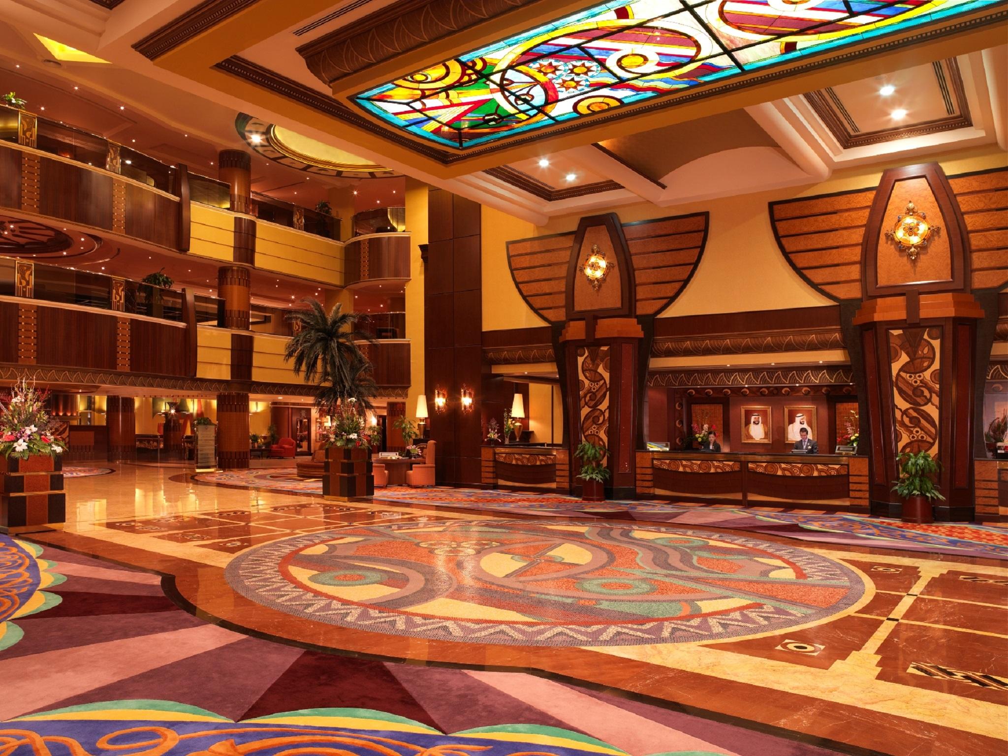 فندق شاطئ الراحة أبو ظبي المظهر الداخلي الصورة The photo depicts an elegantly designed hotel lobby. It features a grand ceiling with intricate stained glass and decorative patterns. The floor is adorned with colorful, ornate designs, including circular patterns. The lobby is spacious, with wooden