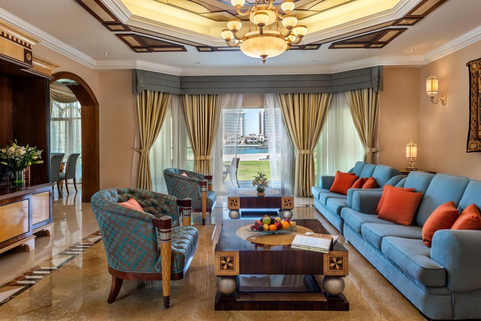 فندق شاطئ الراحة أبو ظبي المظهر الخارجي الصورة The photo depicts an elegantly designed living room with a sophisticated atmosphere. It features a large, light blue sofa adorned with orange and blue cushions. There are two stylish armchairs nearby with a unique pattern. In the center, a coffee tab