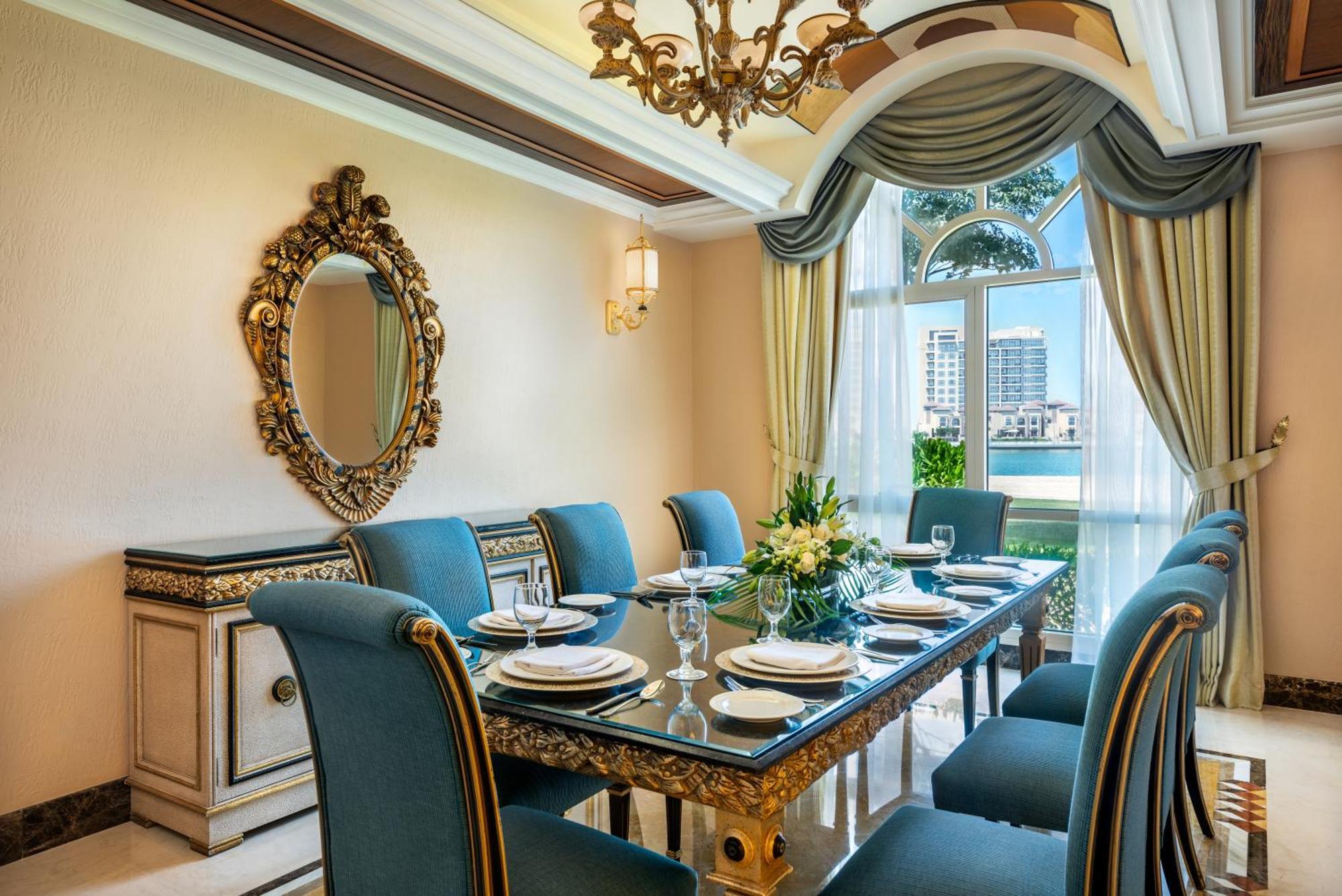 فندق شاطئ الراحة أبو ظبي المظهر الخارجي الصورة The photo features an elegantly decorated dining room. It includes a long, polished table set for a meal with plates, glasses, and decorative items, surrounded by plush blue chairs. The room is adorned with sophisticated details, such as an ornate mi