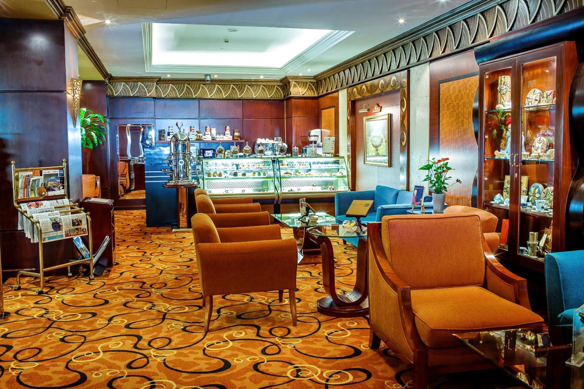 فندق شاطئ الراحة أبو ظبي المظهر الخارجي الصورة The photo shows a cozy and elegantly designed lounge or café area. It features plush seating with brown armchairs and a blue couch. In the background, there is a display case filled with various items, likely including pastries or decorative goods. T
