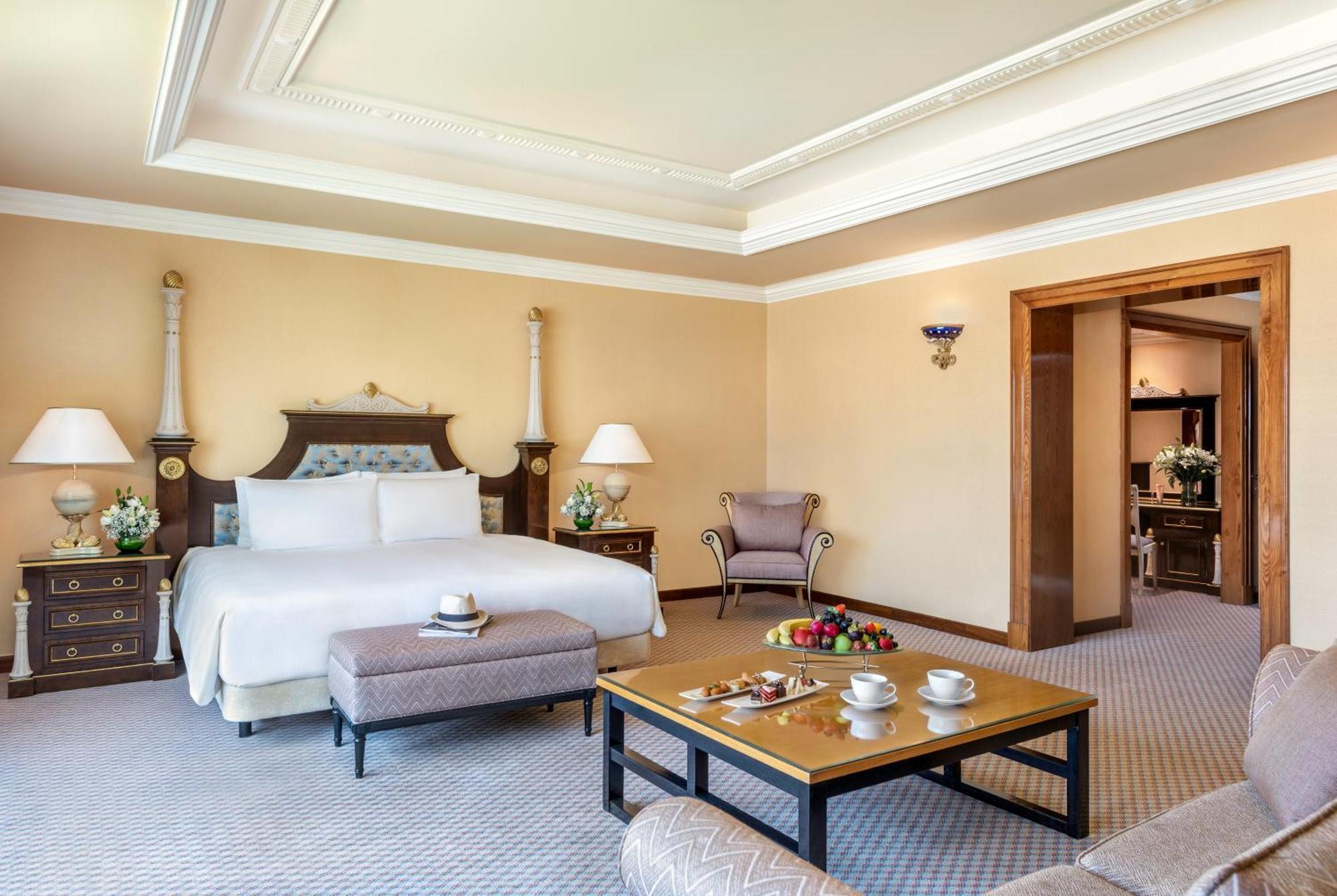 فندق شاطئ الراحة أبو ظبي المظهر الخارجي الصورة The photo shows an elegant hotel room, featuring a large bed with white linens, flanked by stylish bedside tables and lamps. The room has a warm color palette, with light brown walls and a plush carpet. A comfortable armchair is positioned nearby, an