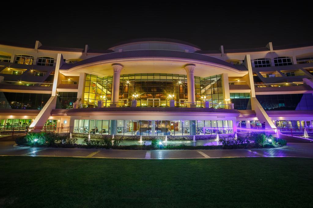 فندق شاطئ الراحة أبو ظبي المظهر الخارجي الصورة The photo shows a modern architectural building illuminated at night. The structure has a large central entrance with multiple glass windows, flanked by symmetrical columns. The exterior features a combination of sleek lines and curves, with lighting